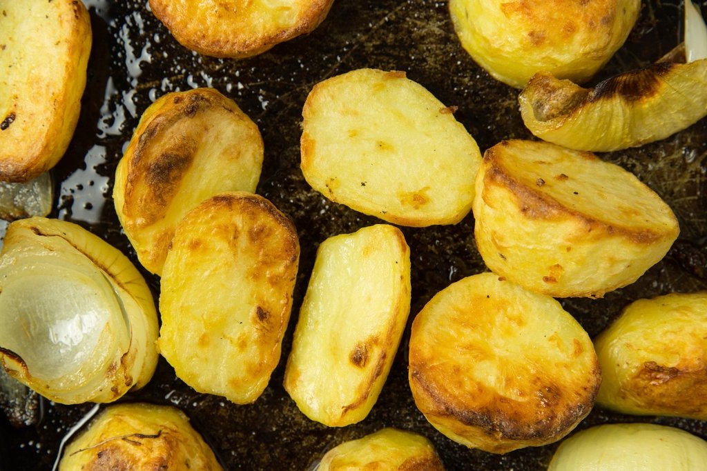 Roast potatoes and onion in a roasting tin with dark cooking fat and juices left in the bottom of the tray